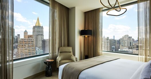 The Madison Suite Bedroom at the Ritz Carlton NoMad, featuring a palette of brown and bronze and a view of New York City. 