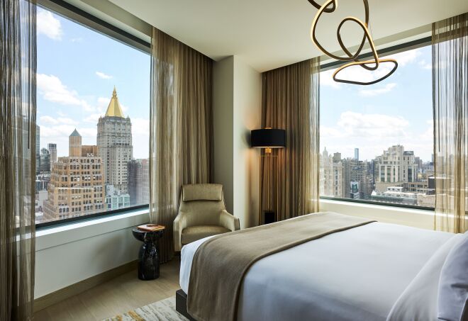 The Madison Suite Bedroom at the Ritz Carlton NoMad, featuring a palette of brown and bronze and a view of New York City. 