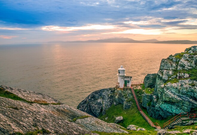 A lighthouse overlooking the ocean at sunset in West Cork, Ireland