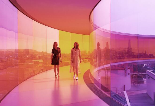 A couple walk through a purple and orange glass walkway