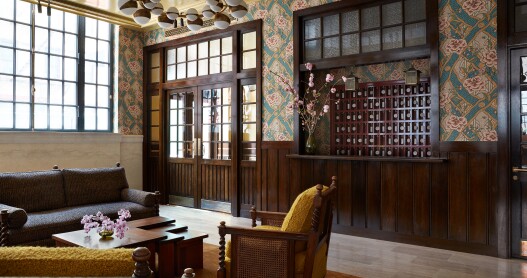 The lobby of the Nine Orchard in New York City features nubby yellow couches and shares and floral wallpaper. 