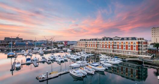 Cape Grace, A Fairmont Managed Hotel, sits on Cape Town's charming waterfront and has a red exterior.